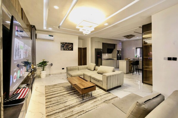A modern living room with a sectional sofa, a wooden coffee table, and a flat-screen TV.
