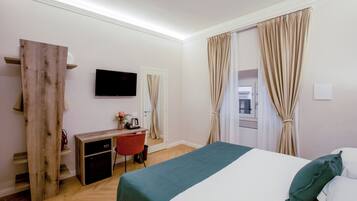 Una habitación de hotel con cama, escritorio, silla, televisor y cortinas.