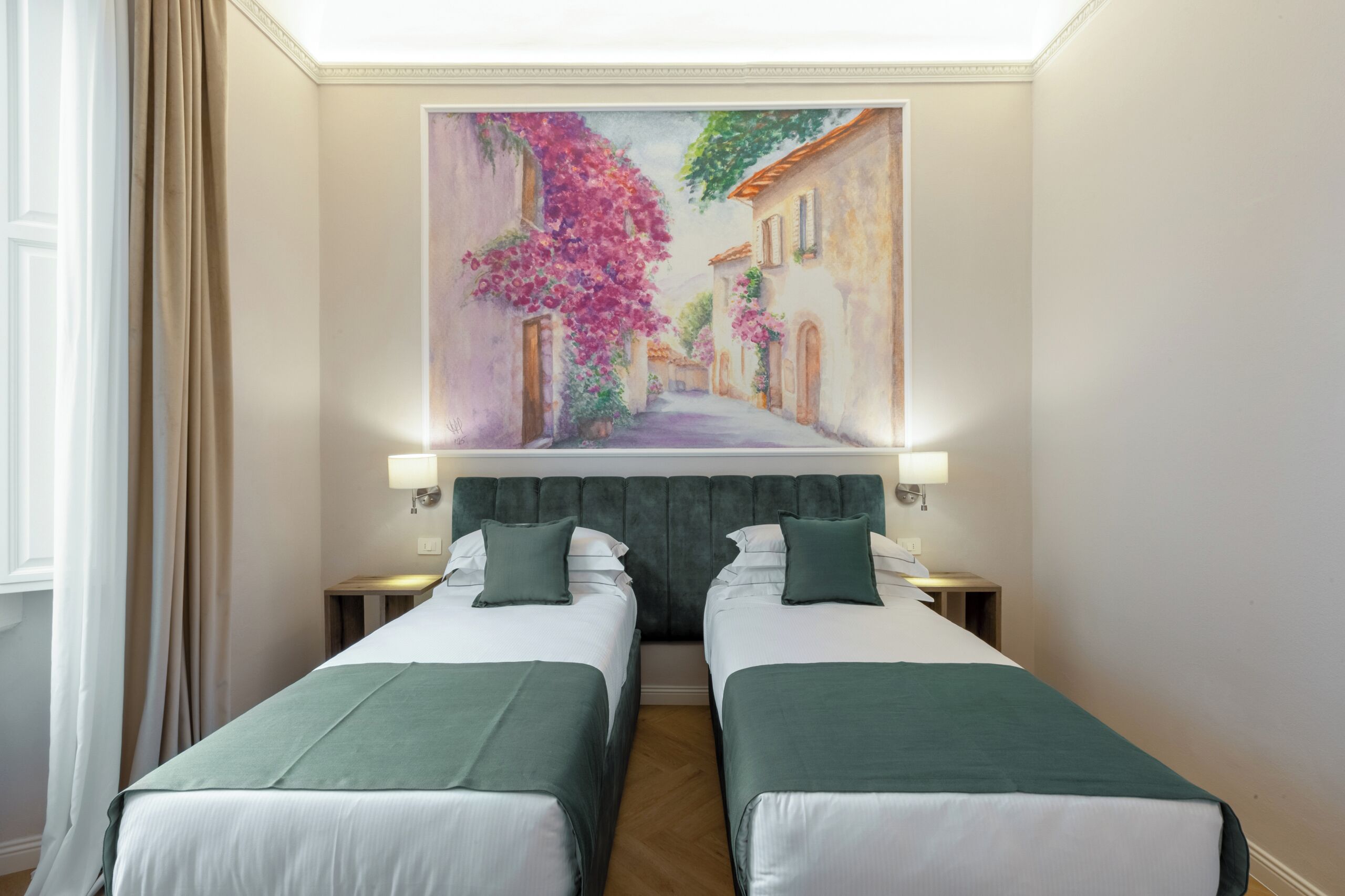 A hotel room with two beds, a painting of a street scene, and a window with curtains.