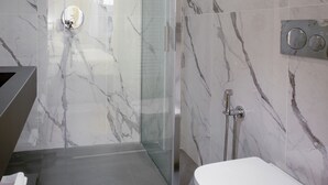 A modern bathroom with a glass shower enclosure, a white toilet, and marble walls. - Hotel Settefiori (Florence)