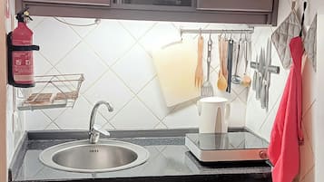 Una cocina con armarios de madera, un fregadero y varios utensilios colgados en la pared.