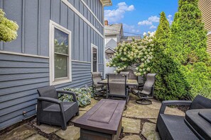 A patio with outdoor furniture, a stone table, and a flower arrangement. - Beach House with Hot Tub and Golf Cart (South Haven)
