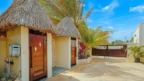A tropical resort with thatched-roof structures, a gated entrance, and a water pump. - EVA Aruba Boutique Resort & SPA (Savaneta)