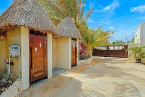 A tropical resort with thatched-roof structures, a gated entrance, and a water pump. - EVA Aruba Boutique Resort & SPA (Savaneta)