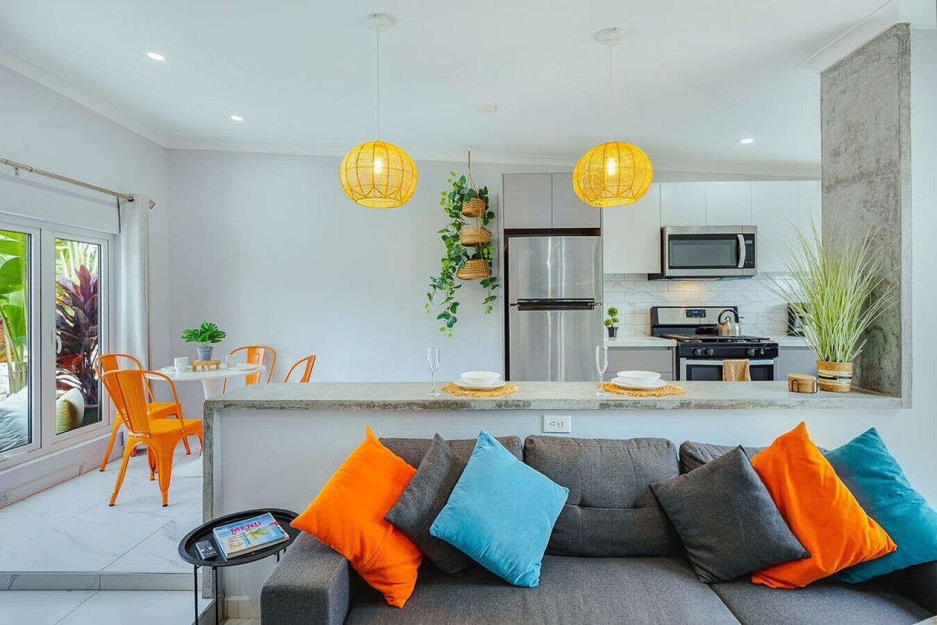 Cozinha moderna com ilha central, eletrodomésticos de aço inoxidável e luminárias pendentes.
