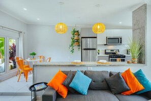 A modern kitchen with a central island, stainless steel appliances, and hanging pendant lights. - EVA Aruba Boutique Resort & SPA (Savaneta)