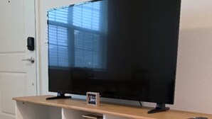 Ein Fernseher auf einem Holzboden mit Ablagefläche darunter.