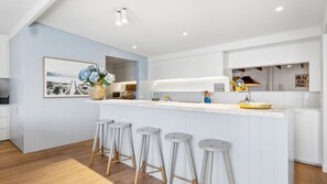 A modern kitchen with a central island, bar stools, and a large window. - Somerset - Portsea - Coastal Escape with Private Beach Access (Portsea)