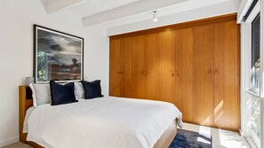 A bedroom with a bed, a large wardrobe, a framed picture, and a window. - Somerset - Portsea - Coastal Escape with Private Beach Access (Portsea)