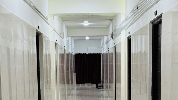 A long, narrow hallway with shiny tiled floors and walls, leading to a dark curtain at the end.