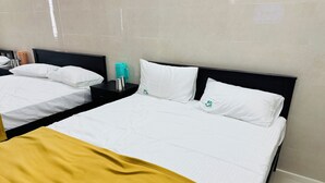 A hotel room with two beds, a yellow throw blanket, and a teal water bottle on a nightstand.