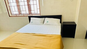 A neatly made bed with a yellow blanket, white pillows, and a black headboard.