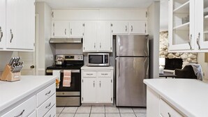 Una cocina moderna con armarios blancos, electrodomésticos de acero inoxidable y un salpicadero de pared de piedra.