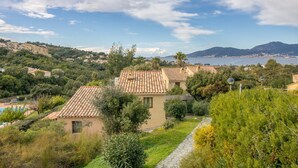 Eine Küstenvilla mit Ziegeldach, umgeben von üppiger Vegetation und freiem Blick auf das Meer.