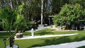 Ein Golfplatz mit Putting Green, Sandfalle und einer Statue.