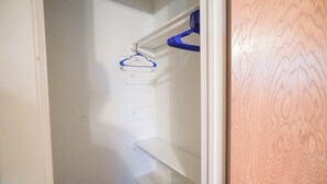 A closet with a blue hanger on a white shelf.