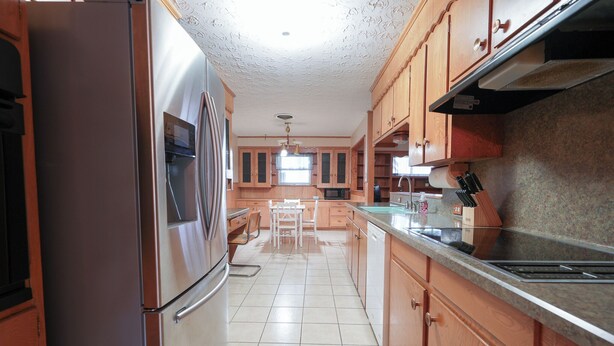 A kitchen with wooden cabinets, stainless steel appliances, and a tiled floor.