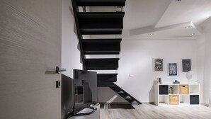 Ein modernes Interieur mit einer Treppe, einem weißen Konsolentisch und einer Wand mit gerahmten Kunstwerken.