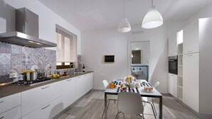 Eine moderne Küche mit weißen Schränken, einem Gasherd und einem Essbereich mit Tisch und Stühlen.