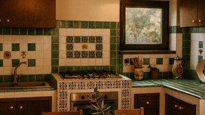 A kitchen with a gas stove, oven, and sink. There is a window above the sink and a decorative tile backsplash. - OLD RENOVATED COTTAGE NESTLED IN THE COUNTRYSIDE WITH GARDEN/RELAXATION CORNER (Adrano)