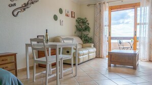 A living room with a dining table, chairs, a sofa, a small table, and a potted plant. - Port Royale Ocean Views Los Cristianos (Los Cristianos)