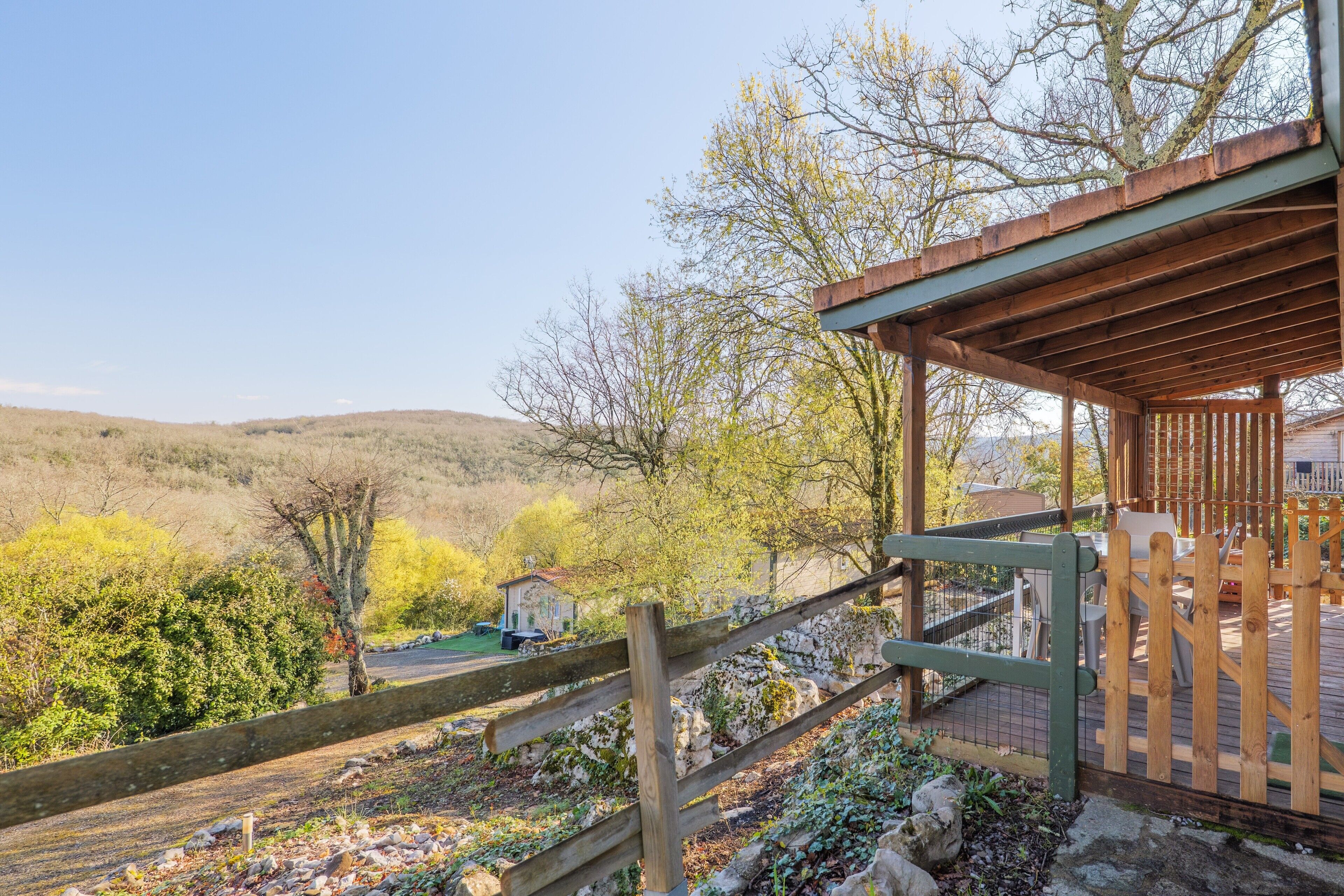 Une terrasse en bois offrant une vue sur un paysage vallonné.
