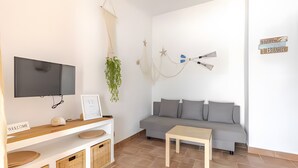 A modern living room with a flat-screen TV, a sofa, a small table, a welcome sign, and wall decorations. - Apartment 'Villa Estrellas 2' with Shared Pool, Private Terrace, and Wi-Fi (Cap d'Artrutx)