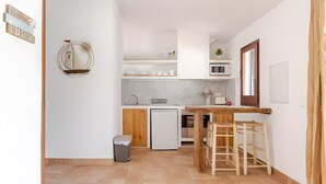 A compact kitchen with a microwave, sink, and wooden stools. - Apartment 'Villa Estrellas 2' with Shared Pool, Private Terrace, and Wi-Fi (Cap d'Artrutx)