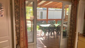 Eine Glastür öffnet sich zu einer Terrasse mit Tisch und Stühlen.