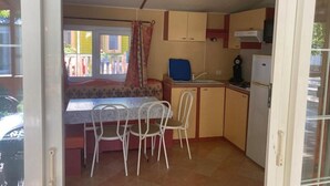 Eine kleine Küche mit Essbereich, Spüle und Kühlschrank.
