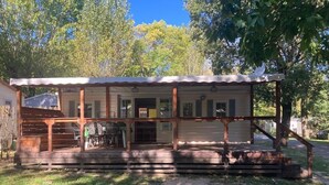 Eine Holzhütte mit Veranda, überdachter Eingangspartei und einer kleinen Sitzgruppe im Freien.