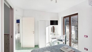 Une chambre à coucher comprenant un lit, un bureau, un miroir et une porte-fenêtre coulissante donnant sur un balcon.