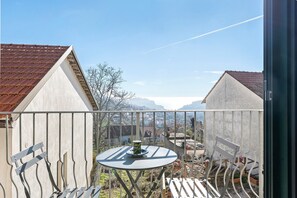 Een balkon met een tafel en stoelen, uitzicht op een berg en een heldere lucht.