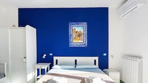 A bedroom with a bed, white nightstands, a radiator, and a blue wall with a framed picture. - Room 'Amalfi' with Sea View, Wi-Fi and Air Conditioning (Agerola)