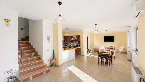 A spacious living area with a kitchen, dining table, and a staircase. - Room 'Amalfi' with Sea View, Wi-Fi and Air Conditioning (Agerola)