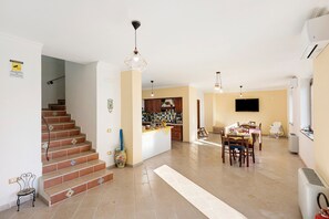 Uma sala de estar espaçosa com cozinha, mesa de jantar e escada.