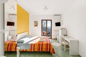 Une chambre avec deux lits, un bureau et une vue sur l’extérieur, visible à travers une porte.