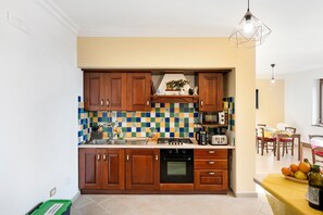 Une cuisine avec des meubles de rangement en bois, un pare-feu en carrelage, une cuisinière et un coin repas comprenant une table et des chaises.