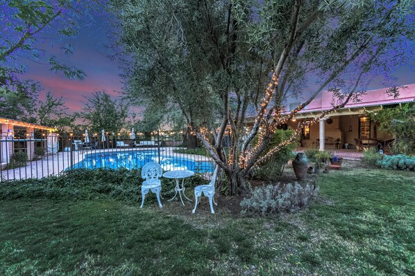 A pool area with a fence, outdoor seating, and string lights.