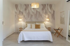 A bedroom with a large bed, two bedside tables, a hanging light fixture, and a wall-mounted macrame decoration. - Respira Amalfi Coast (Vietri sul Mare)