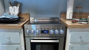 Eine Küche mit einem Edelstahlbackofen, einer digitalen Uhr und einer Holzarbeitsplatte.