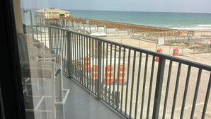 Ein Balkon mit Blick auf den Strand, ausgestattet mit einer Brüstung und orangefarbenen Absperrkeilen.