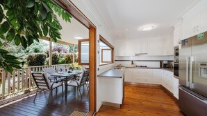 A modern kitchen with white cabinets, stainless steel appliances, and a wooden deck with outdoor seating. - A Market Place Mudgee Walk to Town Centre and Parks (Mudgee)