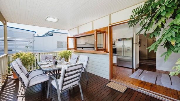 A covered outdoor dining area with a table and chairs, a wooden deck, and a view of the kitchen through a glass door. - A Market Place Mudgee Walk to Town Centre and Parks (Mudgee)