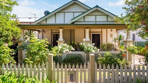 A two-story house with a green roof, white columns, and a white picket fence. - A Market Place Mudgee Walk to Town Centre and Parks (Mudgee)