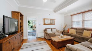 A spacious living room with a television, wooden cabinet, and comfortable seating. - A Market Place Mudgee Walk to Town Centre and Parks (Mudgee)