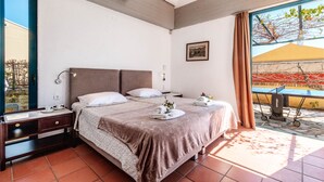 A bedroom with two beds, a desk, and a large window with a view of a building and a tree. - Barbati Beach - Villa Zante (Barbati)
