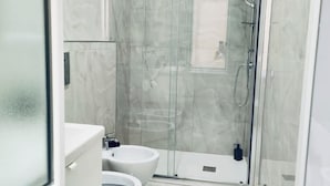 Une salle de bain moderne avec une douche à parois de verre, un lavabo blanc et des toilettes.