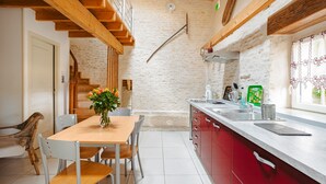 A kitchen with a wooden ceiling, a dining table with chairs, a red cabinet, and a window with curtains. - Gîte L'Etable - Les Gites Du Moulin: private terrace, garden, Wi-Fi in Saint-Hilaire-la-Palud (Saint-Hilaire-la-Palud)
