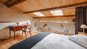 A room with a wooden ceiling, skylights, a bed, a desk, and a chair. - Gîte L'Etable - Les Gites Du Moulin: private terrace, garden, Wi-Fi in Saint-Hilaire-la-Palud (Saint-Hilaire-la-Palud)